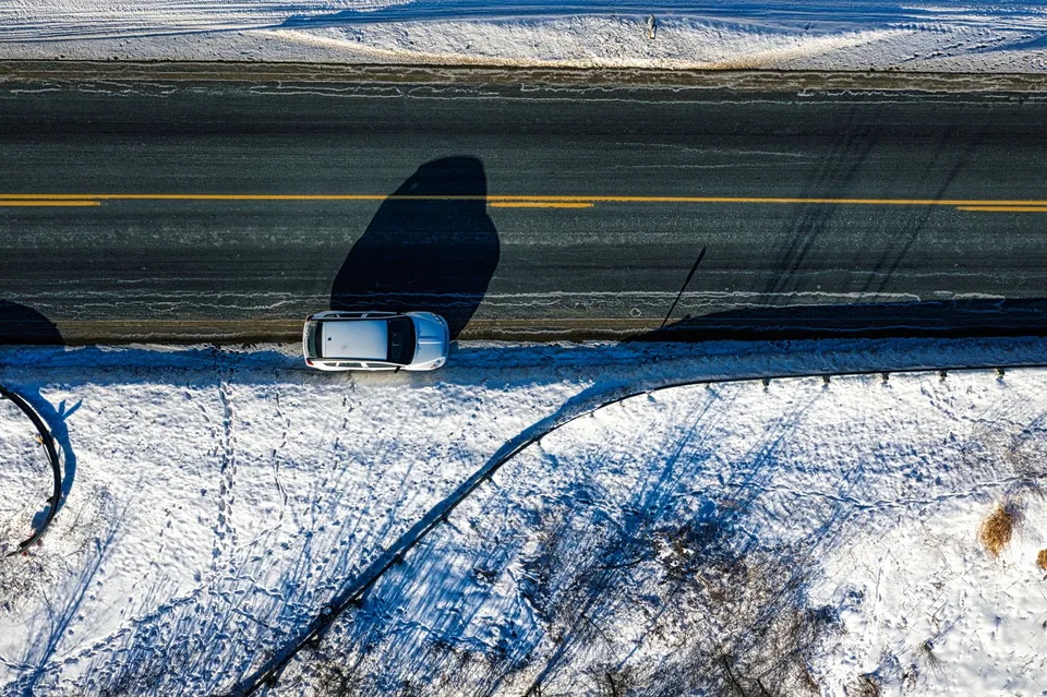 Drone shot of a car on a snow-covered road in Pickwick, Minnesota, during winter.