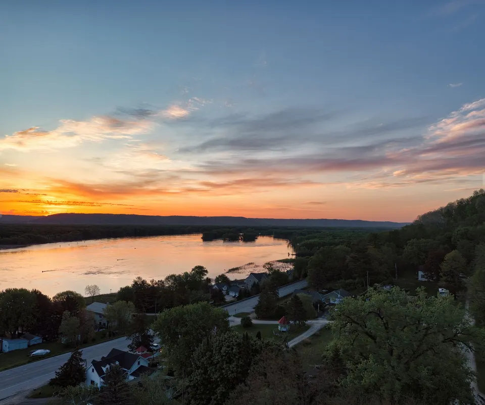 Beautiful aerial view of Reads Landing, MN, at sunset over the Mississippi River with scenic roads and trees.