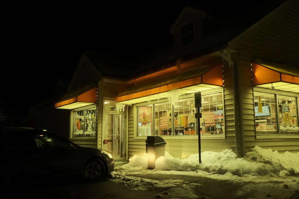 A convenience store at night with snow and icicles, illuminating the street in winter.