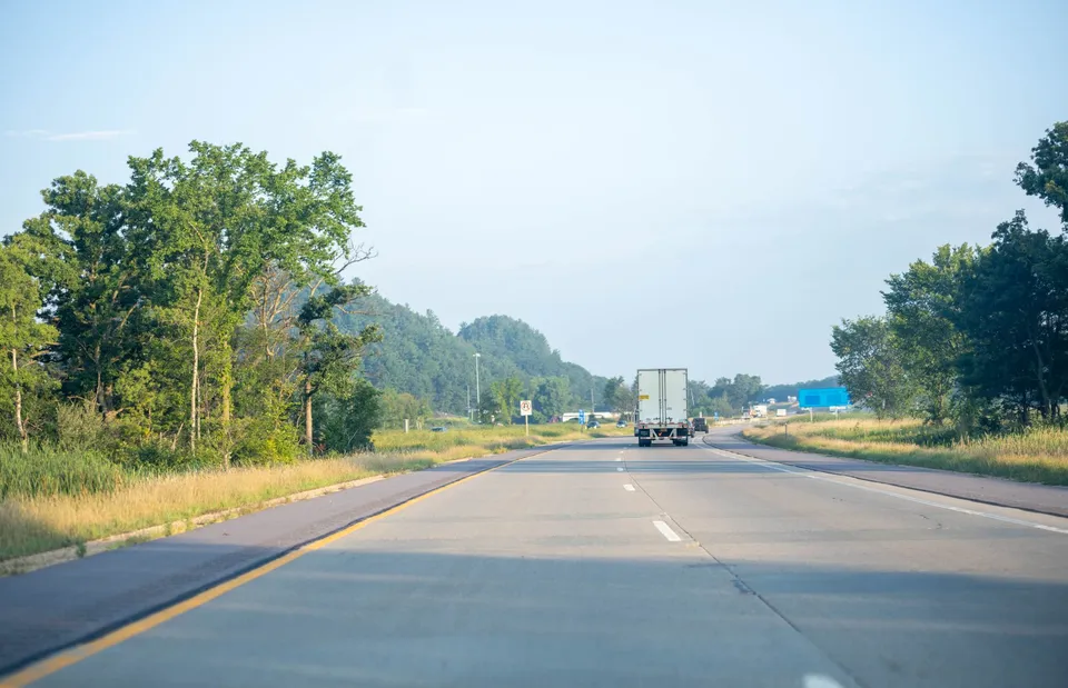 Tranquil highway scene with truck driving in Minnesota's lush summer landscape.
