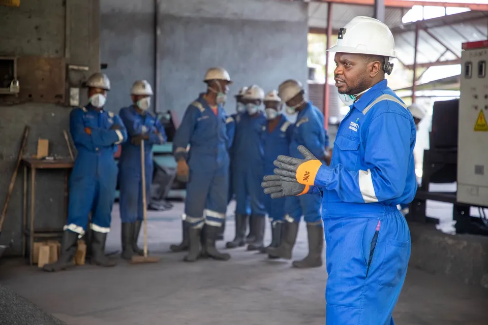 A group of factory workers in safety gear receiving training indoors.